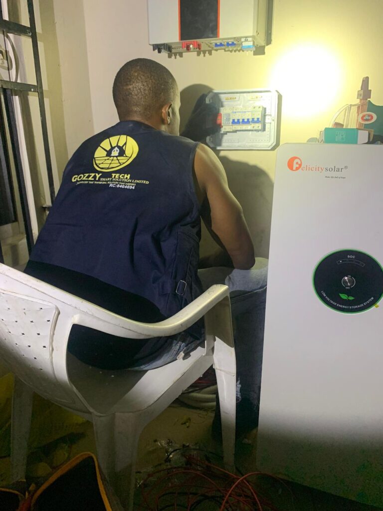 A Gozzy Tech specialist in a branded vest installing a distribution box for a high-capacity Felicitysolar system, providing expert service for affordable solar energy.